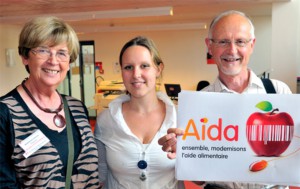 Des bénévoles présentants un panneau avec le logo du logiciel AIDA,  lors de l’assemblée générale de juin 2010